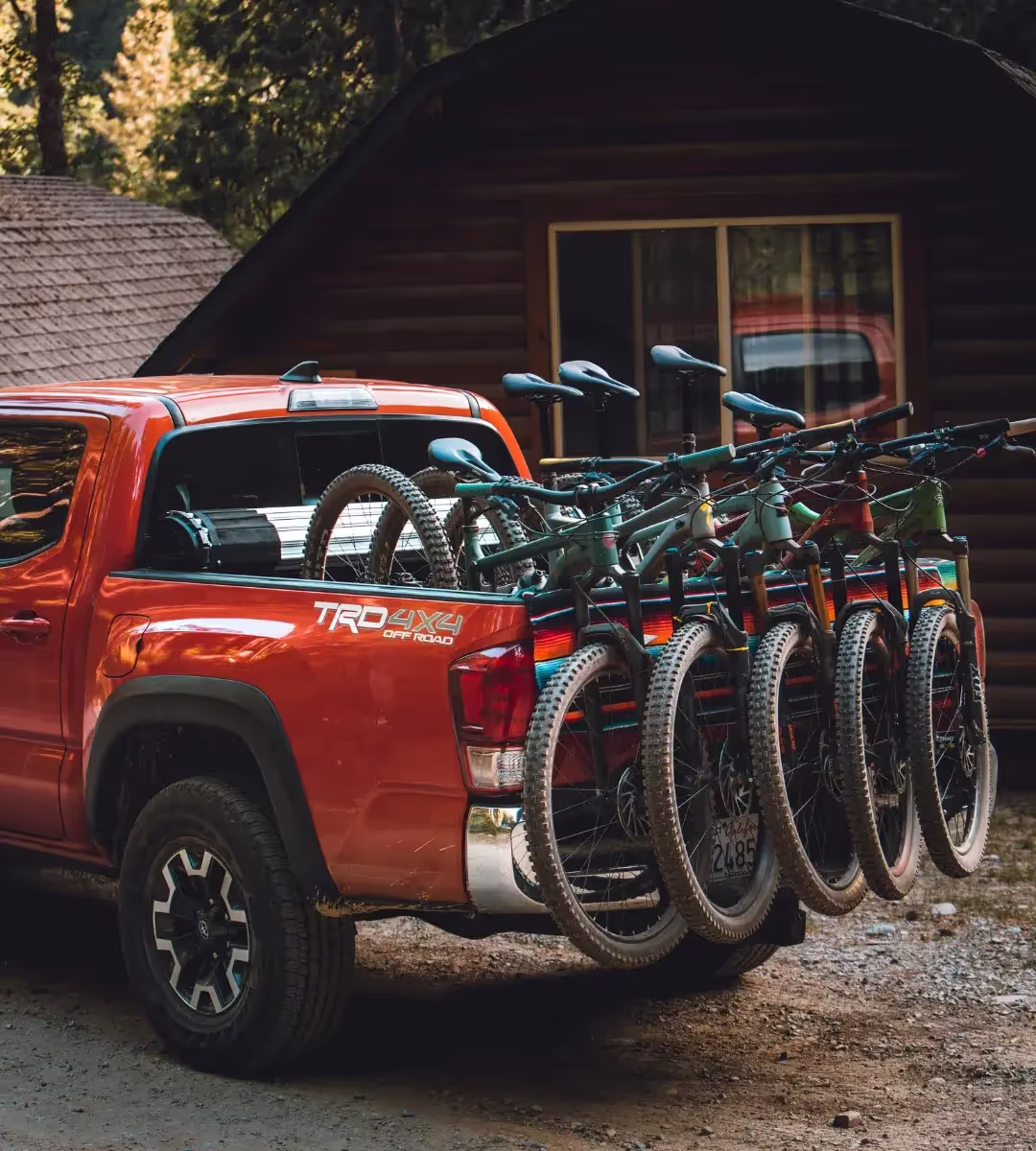 A red pickup truck with multiple bicycles on the load bed