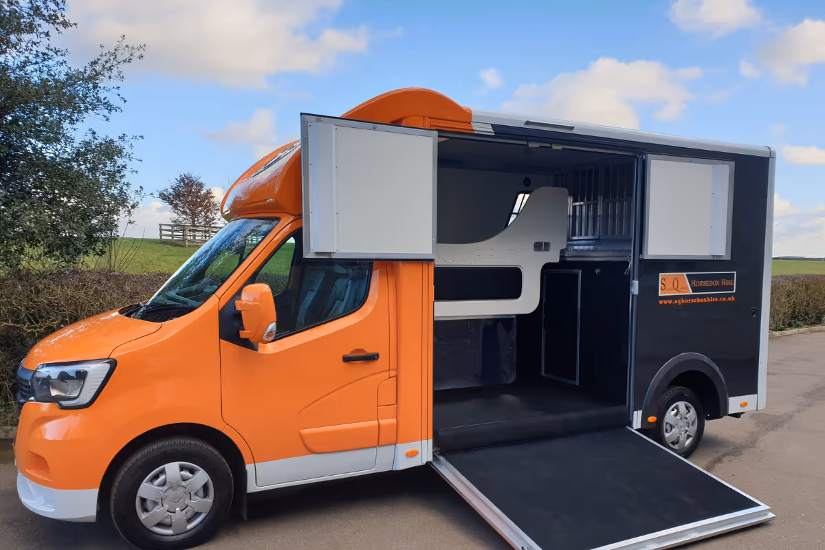 Orange and black horse transport truck with side doors open and ramp deployed.